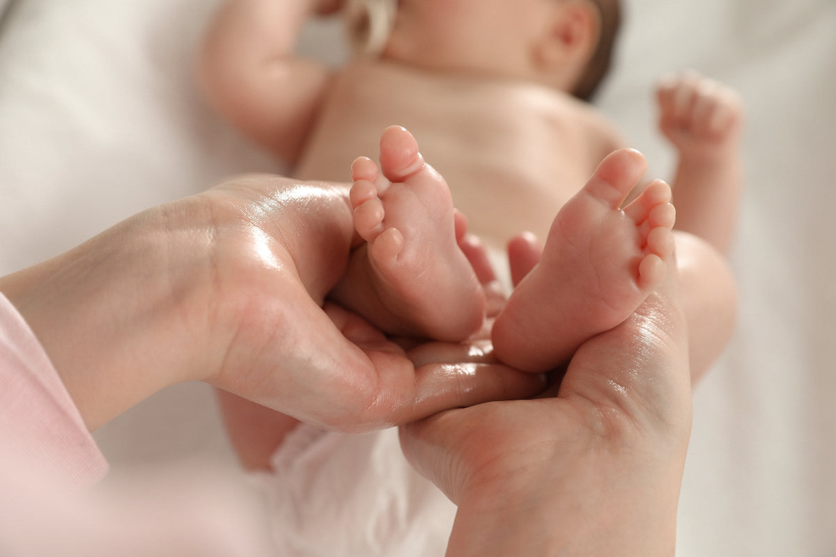 A mother massaging her baby with oil, close up