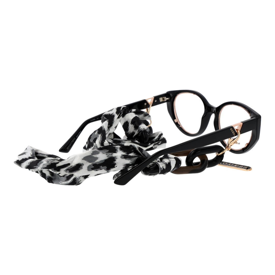 Black and gold cat-eye eyeglasses with thin metal temples and patterned fabric strap laid on white background