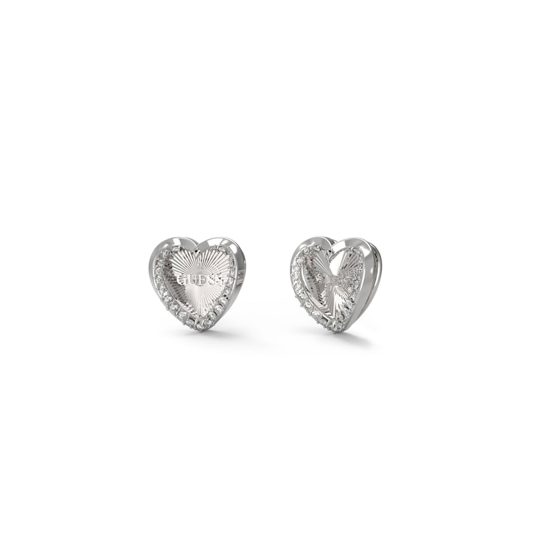 Close-up of silver heart stud earrings with textured centers and a halo of small embedded stones on a neutral background