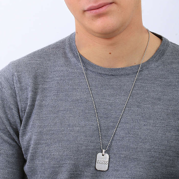 Silver rectangular pendant on ball-link chain laying on neutral background, close-up showing polished finish